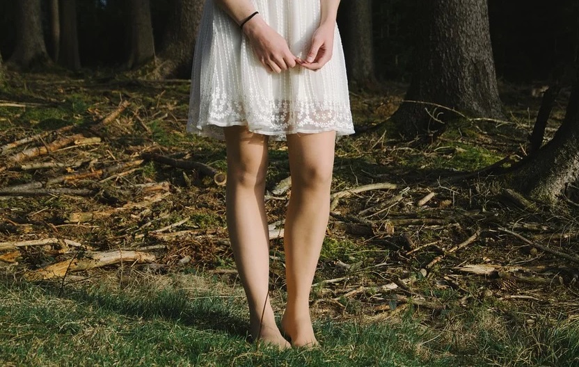 裸足で森の中にたたずむ女性の足元
