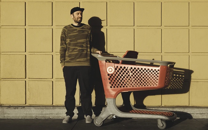 巨大なショッピングカートの横に立つ男性の画像