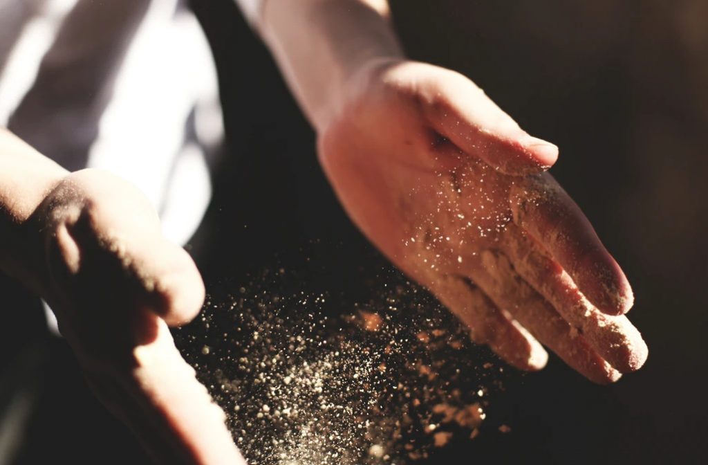 両手についた砂状の粒子をはたいて舞い散る瞬間の画像